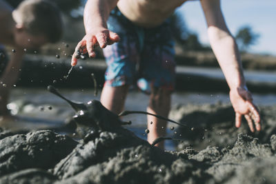 Cropped image of brothers playing in mud at beach