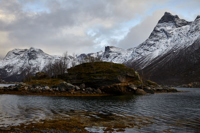 Scenic view of lake by snowcapped mountains against sky