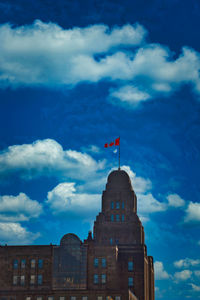 Low angle view of flag on building against cloudy sky