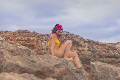 Woman standing on rock against sky