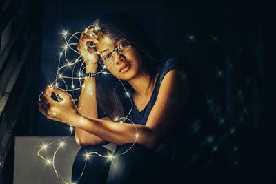 Close-up of smiling woman sitting in illuminated mirror