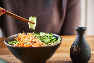 Midsection of man with vegetables in bowl on table