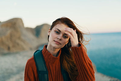 Portrait of beautiful woman at beach against sky