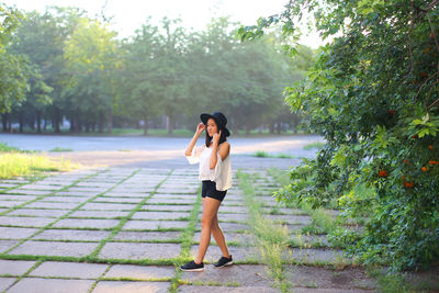 Full length portrait of woman standing on mobile phone