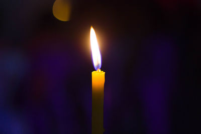 Close-up of lit candle in darkroom