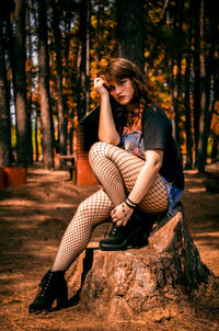 Full length portrait of young woman sitting in forest