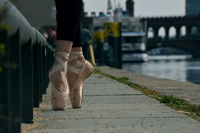 Low section of woman wearing ballet shoes standing on tip toes at promenade