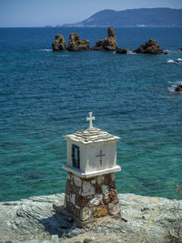 Built structure on rock by sea against sky