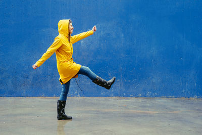 Full length of young woman jumping against wall