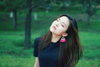 Beautiful young woman with eyes closed standing in forest