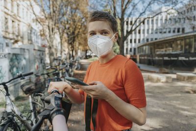 Full length of man holding bicycle standing outdoors