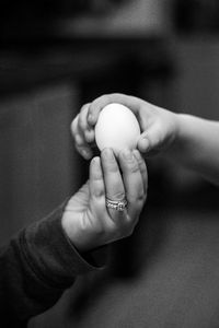 Cropped hand of child with person holding egg