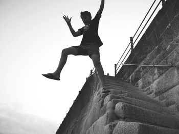 Low angle view of man jumping against sky