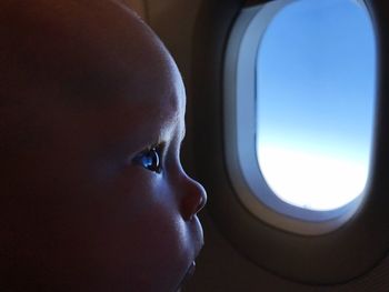 Close-up of boy looking through airplane window