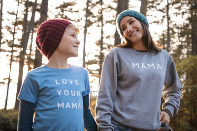 Woman with son smiling against trees during sunset