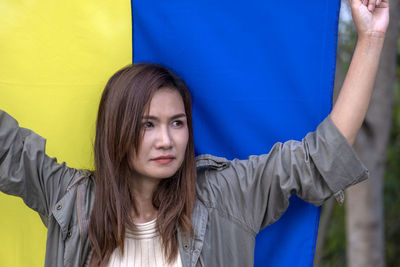 Portrait of smiling young woman standing against wall