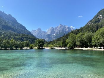 Scenic view of lake and mountains against clear blue sky