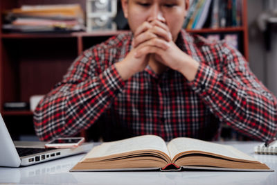 Midsection of man using mobile phone while sitting on table
