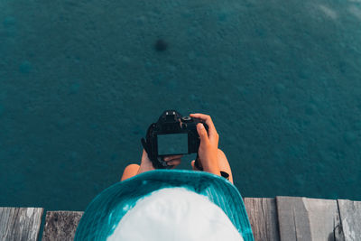 Directly above shot of woman photographing water sitting on pier