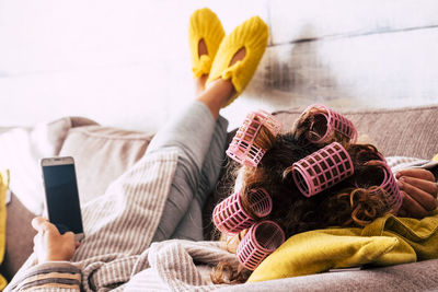 Woman wearing hair curlers while using mobile phone at home