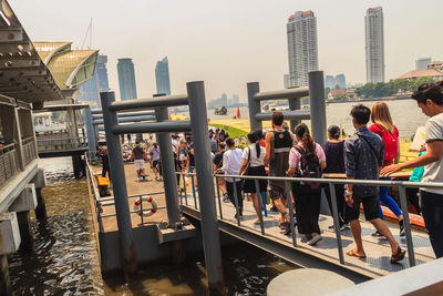 People standing by railing against buildings in city