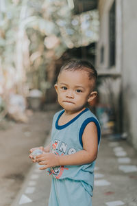 Portrait of cute boy standing on footpath