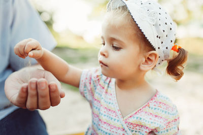 Cute daughter spilling sand on mother hand