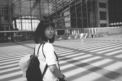 Side view portrait of young woman walking in city