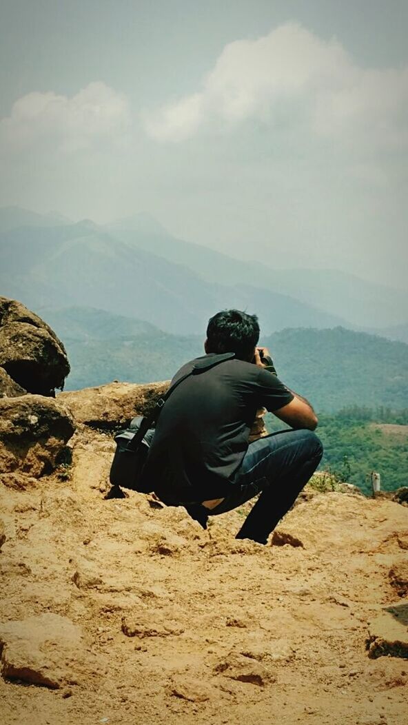 leisure activity, lifestyles, full length, sky, rear view, men, mountain, casual clothing, landscape, tranquil scene, sitting, tranquility, rock - object, nature, beauty in nature, cloud - sky, person, scenics