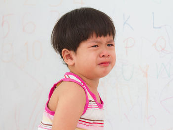 Portrait of cute boy looking away against wall