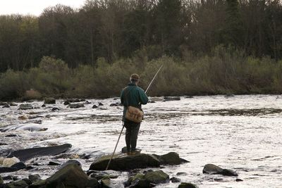 Rear view of man fishing in river