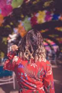 Rear view of woman with brown wavy hair in city