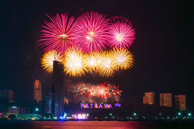 Firework display over city by river at night