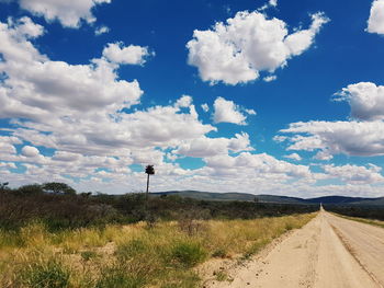 Road amidst field against sky