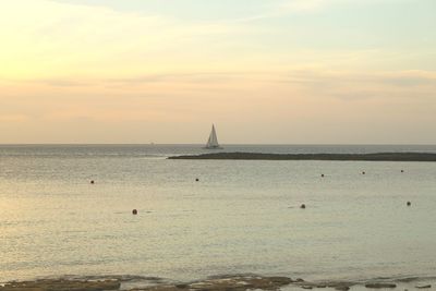 Silhouette sailboat sailing on sea against sky during sunset