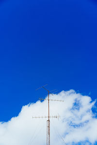 Low angle view of telephone pole against blue sky