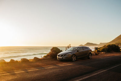 Car on road by sea against clear sky