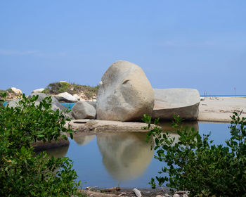 Rocks by lake against sky