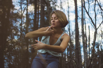 Low angle view of young woman dancing in forest