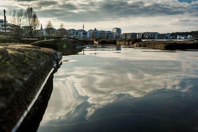 Bridge over river by buildings in city against sky