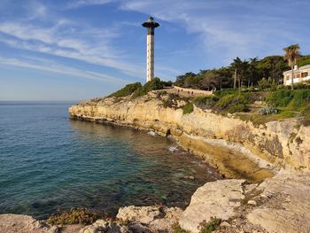 Lighthouse by sea against sky