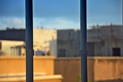 Close-up of metal fence against blue sky