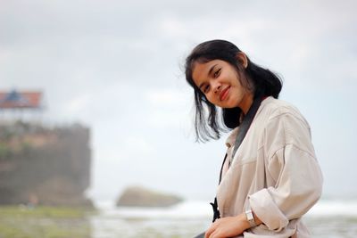 Young woman looking at sea against sky