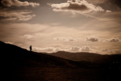 Silhouette man standing on mountain against sky