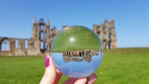 Midsection of person holding umbrella against clear sky