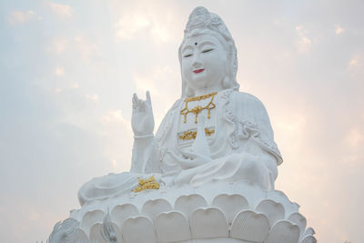 Low angle view of statue against temple building against sky