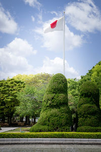 Low angle view of flag amidst trees against sky