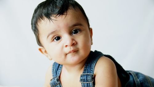 Close-up portrait of cute toddler boy against white background