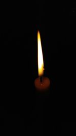 Close-up of lit candle in darkroom