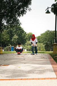 Children riding skateboard and scooter in the park.